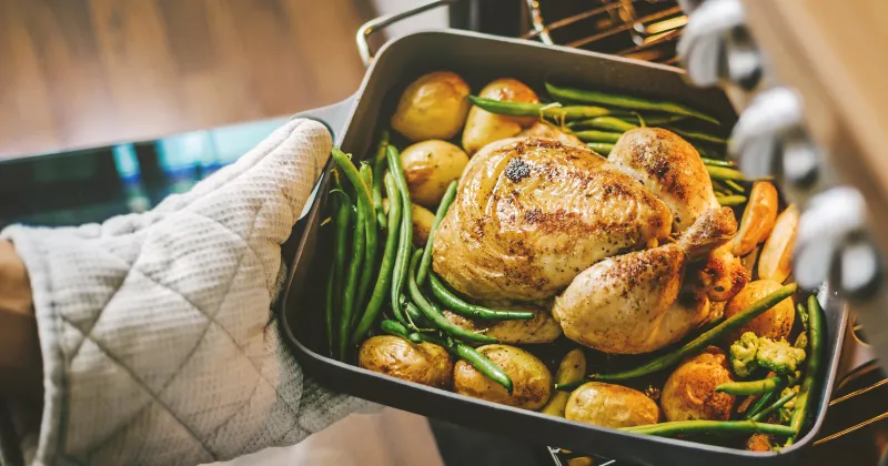 turkey and veggies in a roasting pan coming out of the oven