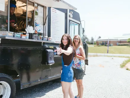 two women eating at a foodtruck