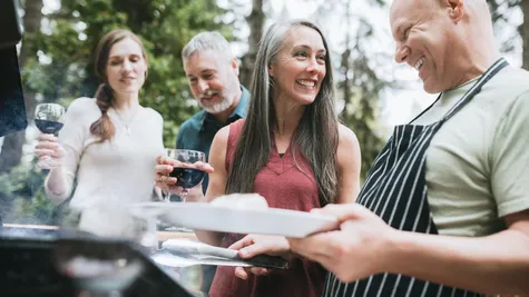 Active adults socializing by a grill with wine