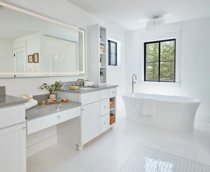 Primary bathroom with a built-in beauty station, quartz countertops, and a freestanding soaking tub.
