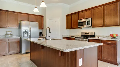 Brown Kitchen Cabinets with Stainless Steel Appliances - Savoy Place - DSLD Homes Gulfport