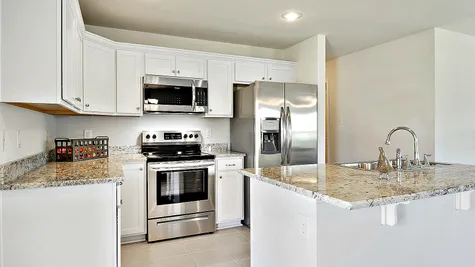 Kitchen with White Cabinets and Stainless Steel Appliances - Belvedere Place - DSLD Homes Gulfport