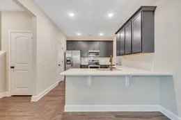 View from the Hatteras dining area into the kitchen, showing a white breakfast bar, dark blue cabinets, stainless steel appliances, and recessed lighting.