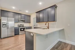 Hatteras kitchen with dark blue cabinets, white countertops, a breakfast bar, bronze-tone faucet, white tile backsplash, and stainless steel appliances.