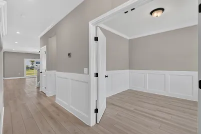 Spacious first-floor den at 186 Hanover Place showcasing double doors, neutral finishes, and abundant natural light from large front windows.