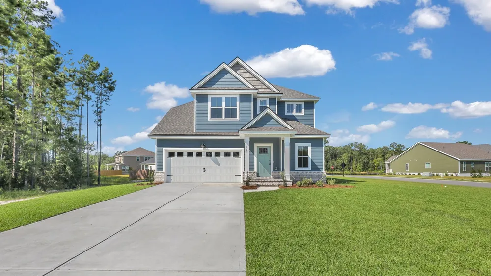 Front view of the Sherwood home featuring blue siding, white gable trim, a light blue front door and a wide driveway leading to the two-car garage.