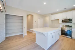 Sherwood kitchen with both pantry doors open to show multiple storage shelves beside the island, white cabinets and stainless steel appliances.
