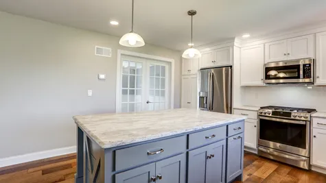 Kitchen with white cabinets and a center island in a remodeled home from Garman builders