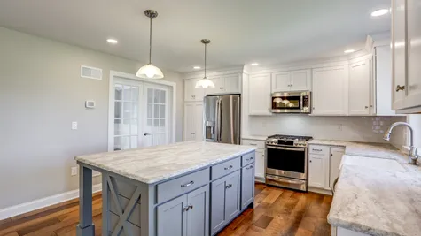 Kitchen with white cabinets and a center island in a remodeled home from Garman builders