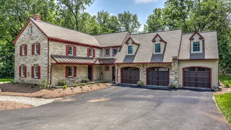Front of a stone home with red accents from Garman builders