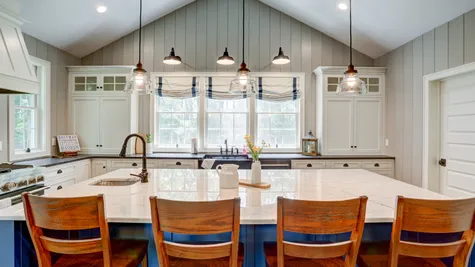 Kitchen with white cabinets and a blue center island in a remodeled home from Garman builders