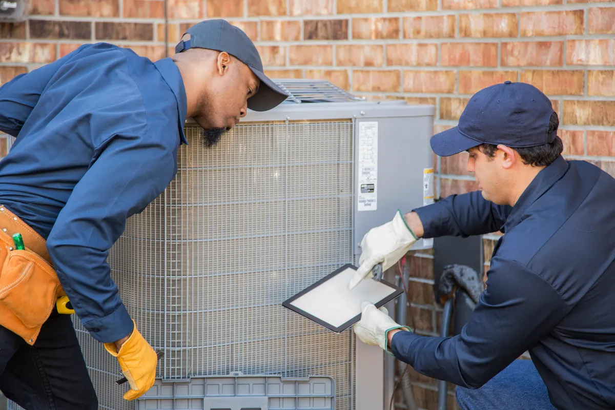Two people looking at an air conditioning unit