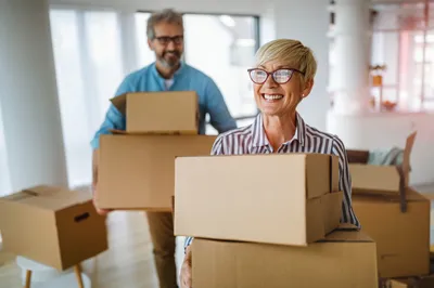 Two people with moving boxes in their new home