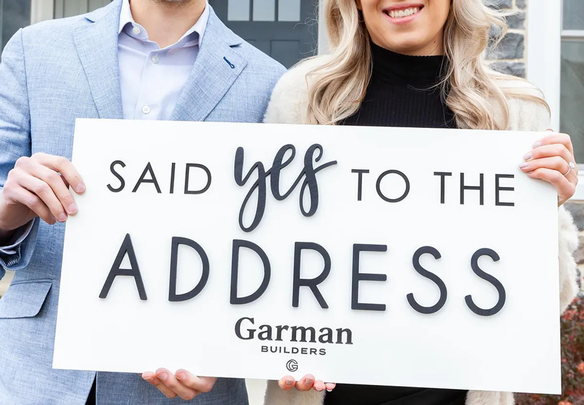 A couple holding a sign that says "said yes to the address"