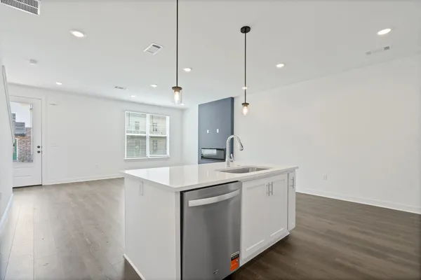 Modern kitchen island with a built-in stainless steel dishwasher, undermount sink, and pendant lighting