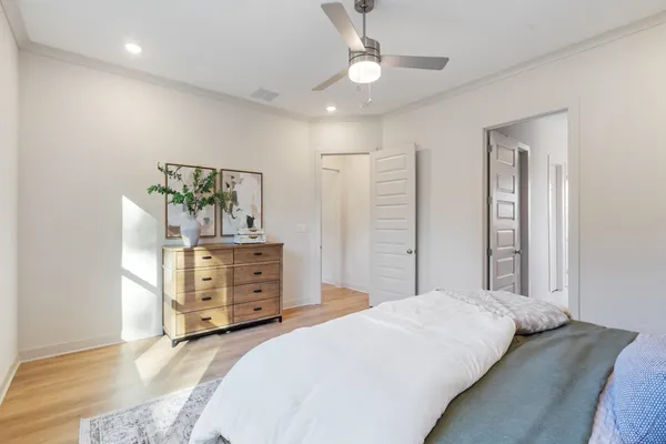 Room featuring wood-finish flooring, recessed lighting, a modern ceiling fan with integrated light, and multiple interior doors with a multi-panel design