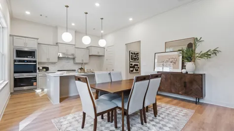 Kitchen featuring a central island, light-toned cabinetry, built-in double ovens, and three pendant lights, complemented by wood-finish flooring