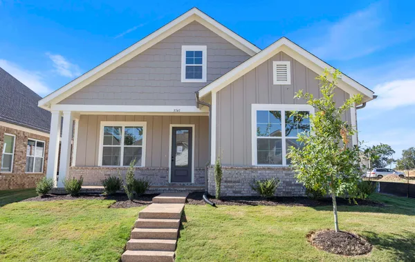 Craftsman-inspired exterior featuring board-and-batten siding, shake shingle gables, a brick veneer base, and a covered front porch with support columns