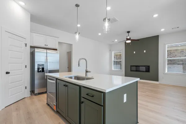 Kitchen island with light-toned countertop, stainless steel appliances, wood-finish flooring, and recessed lighting