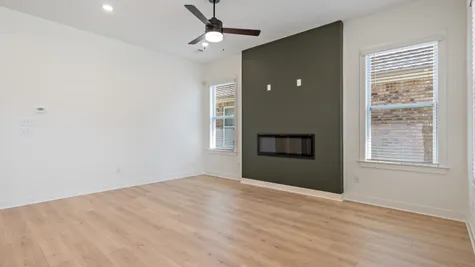 Recessed lighting, wood-finish flooring, a linear electric fireplace, and a ceiling fan with integrated lighting