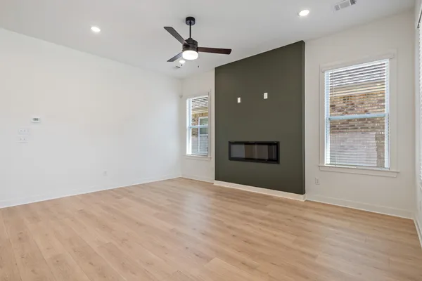 Recessed lighting, wood-finish flooring, a linear electric fireplace, and a ceiling fan with integrated lighting