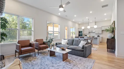 Open-concept living space featuring wood-finish flooring, recessed lighting, a modern ceiling fan, and large windows