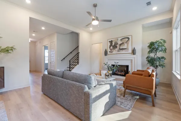 Living area featuring wood-finish flooring, a fireplace with a textured surround, recessed lighting, and a ceiling fan