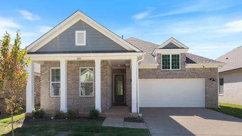 Brick exterior with gray siding accents, covered front porch, white garage door, and a dormer window