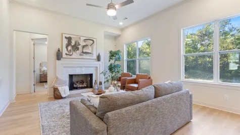 Living area featuring high ceilings, wood-finish flooring, a fireplace with a light-toned tile surround, and large windows