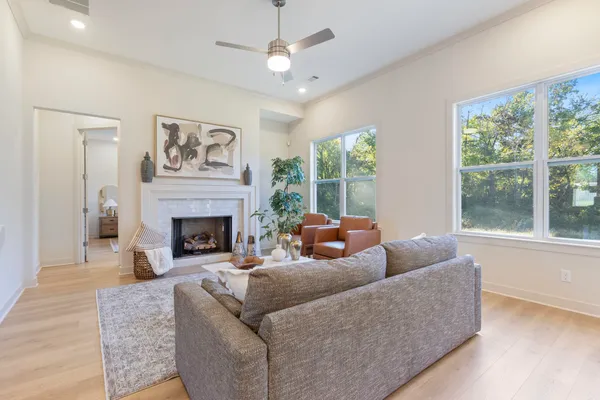 Living area featuring high ceilings, wood-finish flooring, a fireplace with a light-toned tile surround, and large windows