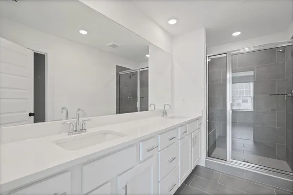 Dual vanity with integrated sinks, white cabinetry, and a full-width mirror