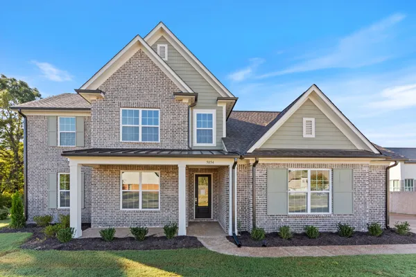 Multi-gabled exterior featuring brick masonry, horizontal siding, decorative shutters, a covered front porch with square columns, and architectural roofing shingles