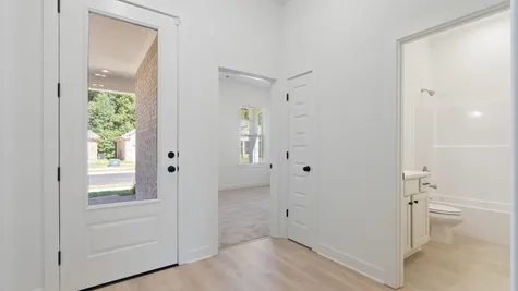 Light wood-finish flooring, white paneled interior doors, and a full-light entry door