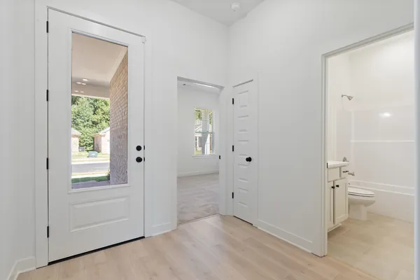 Light wood-finish flooring, white paneled interior doors, and a full-light entry door