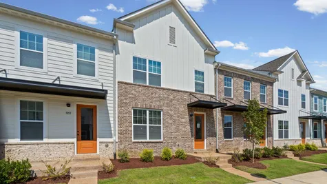 Modern townhome community featuring contemporary architectural design with mixed brick and fiber cement siding exteriors, multi-pane windows, and coordinated orange accent doors