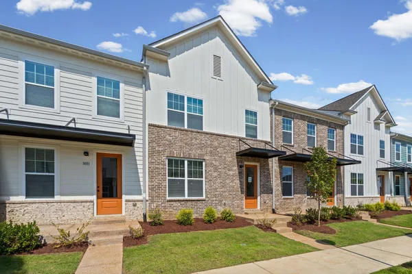 Modern townhome community featuring contemporary architectural design with mixed brick and fiber cement siding exteriors, multi-pane windows, and coordinated orange accent doors