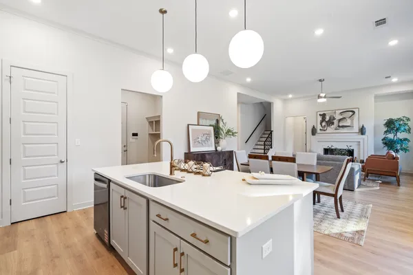 Kitchen island featuring a white countertop, undermount stainless steel sink, and bronze-finish hardware
