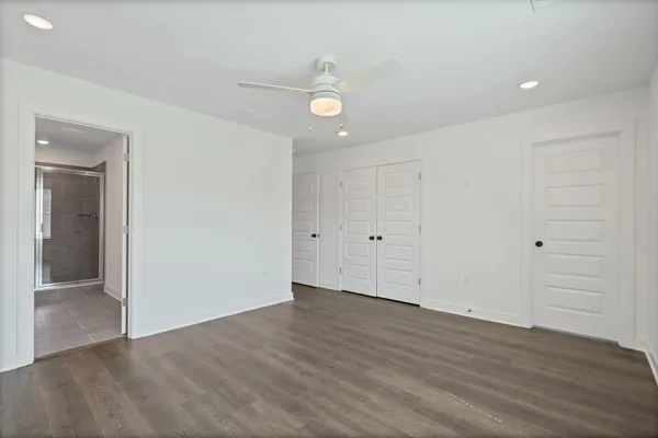 Wood-finish flooring, recessed lighting, ceiling fan, white interior doors, and a tile-floor bathroom with a glass shower enclosure
