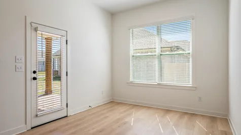 Wood-finish flooring, white walls, and a large window with blinds