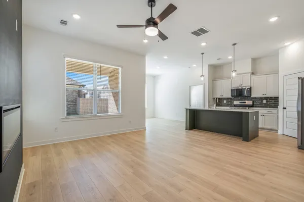 Light wood-finish flooring throughout, recessed lighting, and a ceiling fan