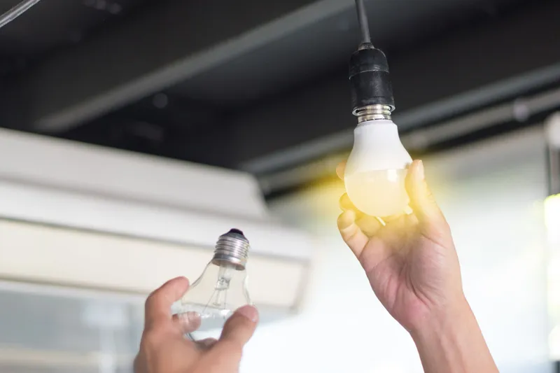 Person screwing in a new lightbulb while holding the old one