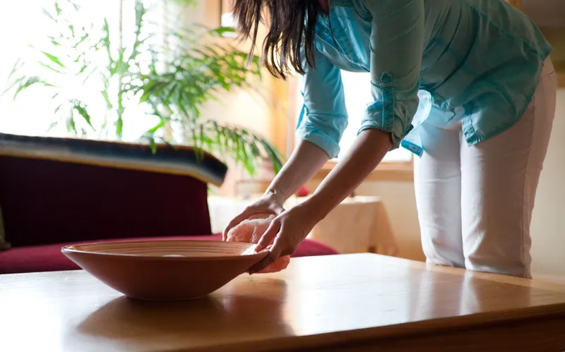 Woman Placing a Wooden bowl on a Table