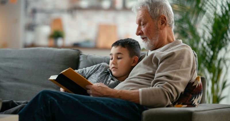 A grandfather reading a book to his grandson.
