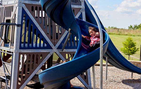 Girl sliding on playground in Native Plains - new homes in Moore, OK