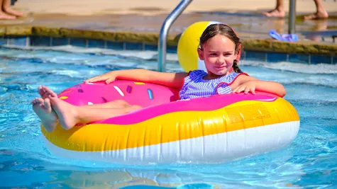 Abernathy. Child floating on a raft in the community pool