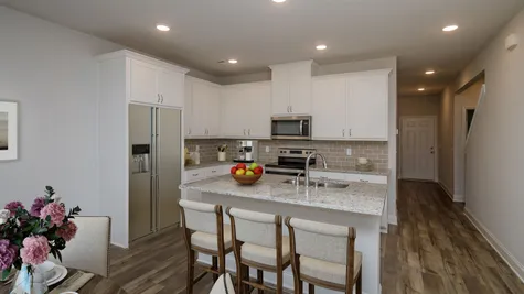 A chic and contemporary kitchen featuring a tile backsplash and stainless steel appliances, part of a new townhome by Ivey Homes located at 1012 Candleberry Drive in Grovetown, GA, with prices starting in the $200s.