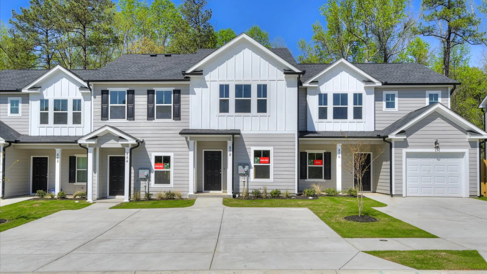 Exterior view of a newly constructed townhome by Ivey Homes at 878 Rachel Branch Forrest Bluff, showcasing the modern design with a backdrop of lush trees in North Augusta, SC.