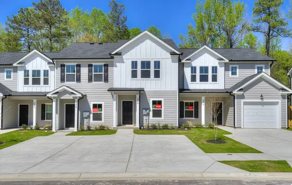Exterior view of a newly constructed townhome by Ivey Homes at 878 Rachel Branch Forrest Bluff, showcasing the modern design with a backdrop of lush trees in North Augusta, SC.