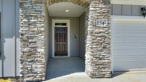 Close-up view of the new construction single-family home's entryway at 854 Rachel Branch Forrest Bluff by Ivey Homes in North Augusta, SC, featuring a stonework arch, craftsman-style wood accents, and an inviting front door, ideal for holiday decorations and greeting guests.