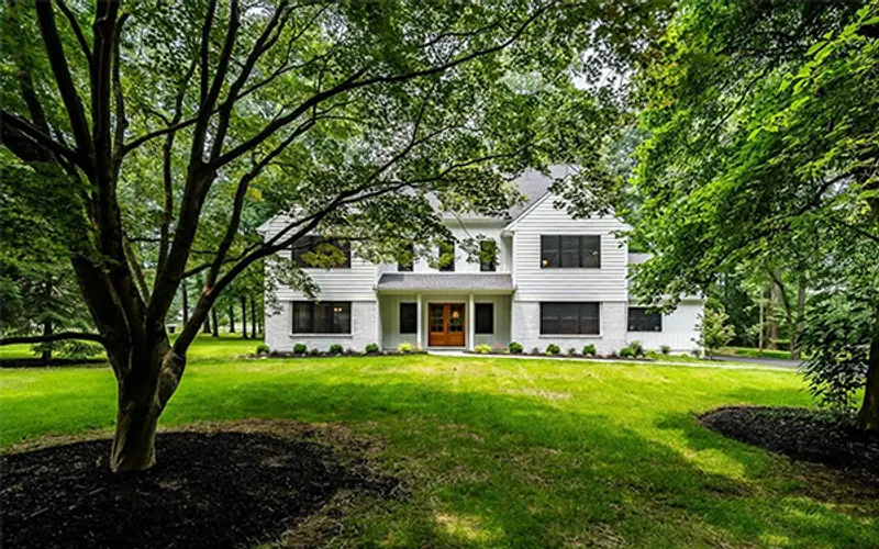 White home surrounded by green lawn and mature trees